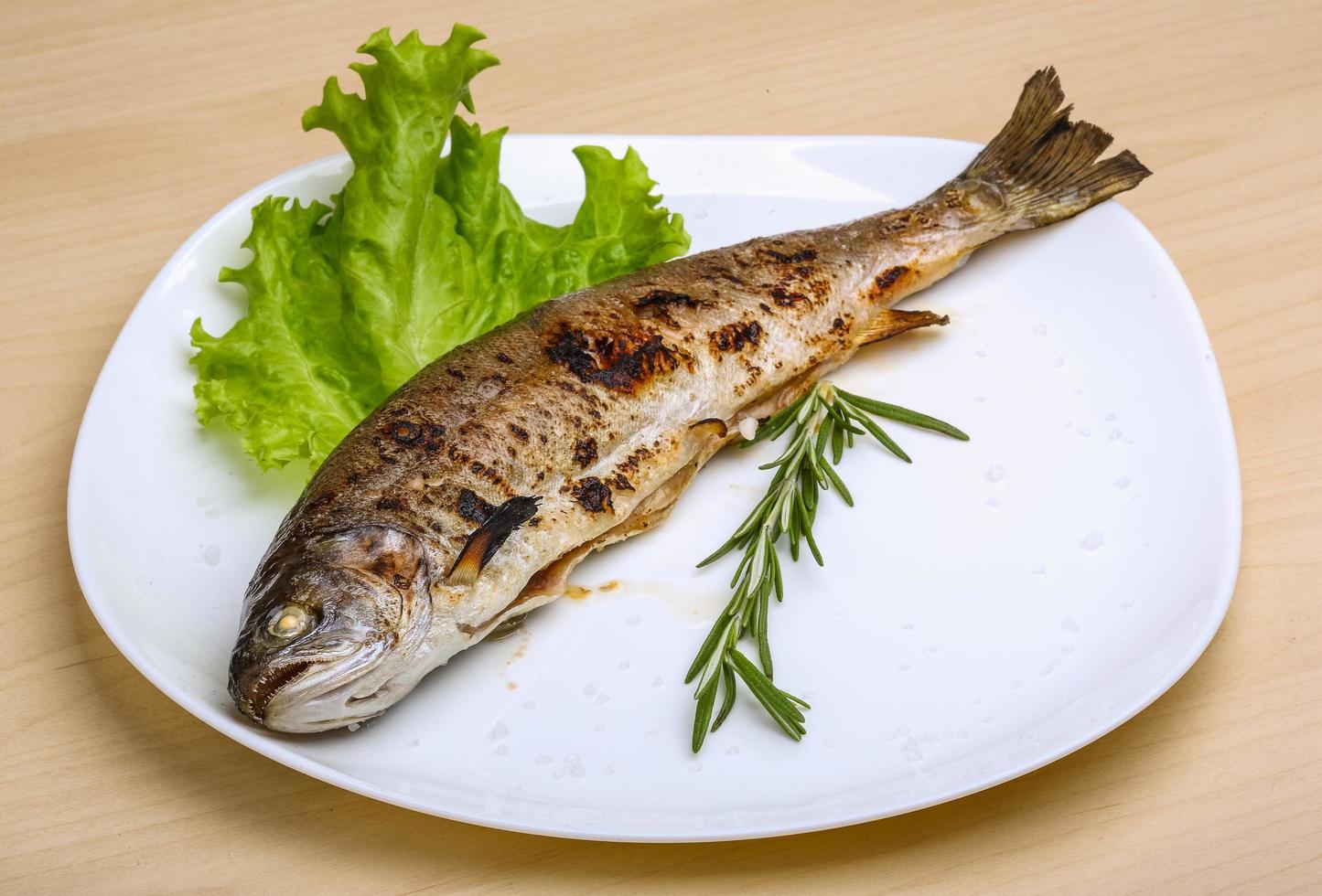 Grilled trout on the plate and wooden background photo