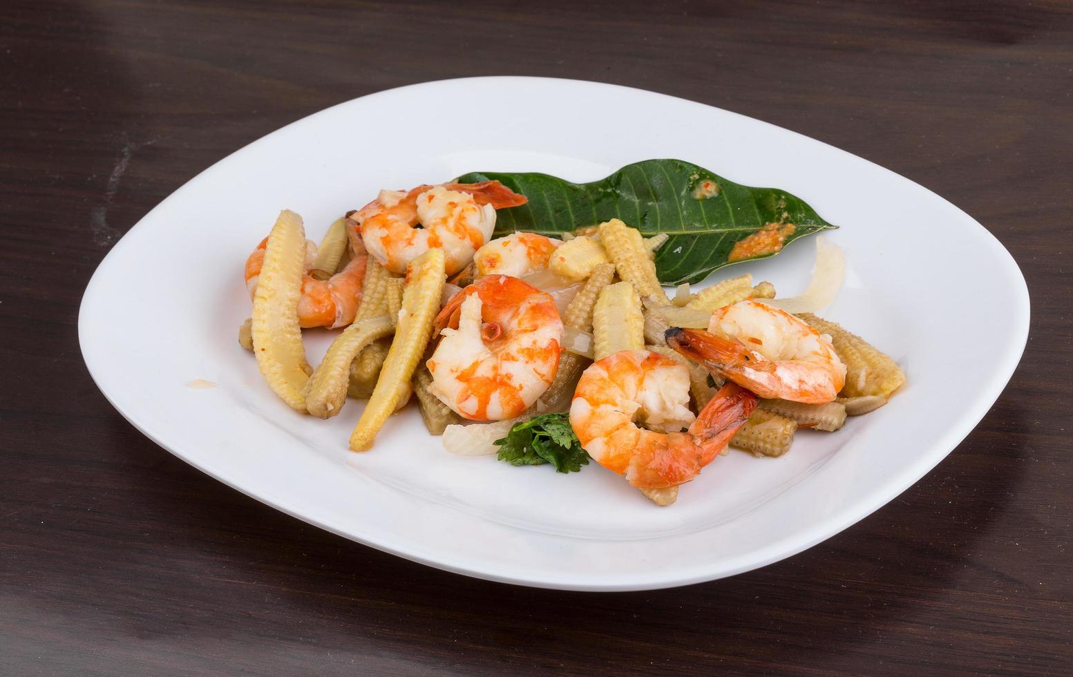 ensalada de camarones y maíz en el plato y fondo de madera foto