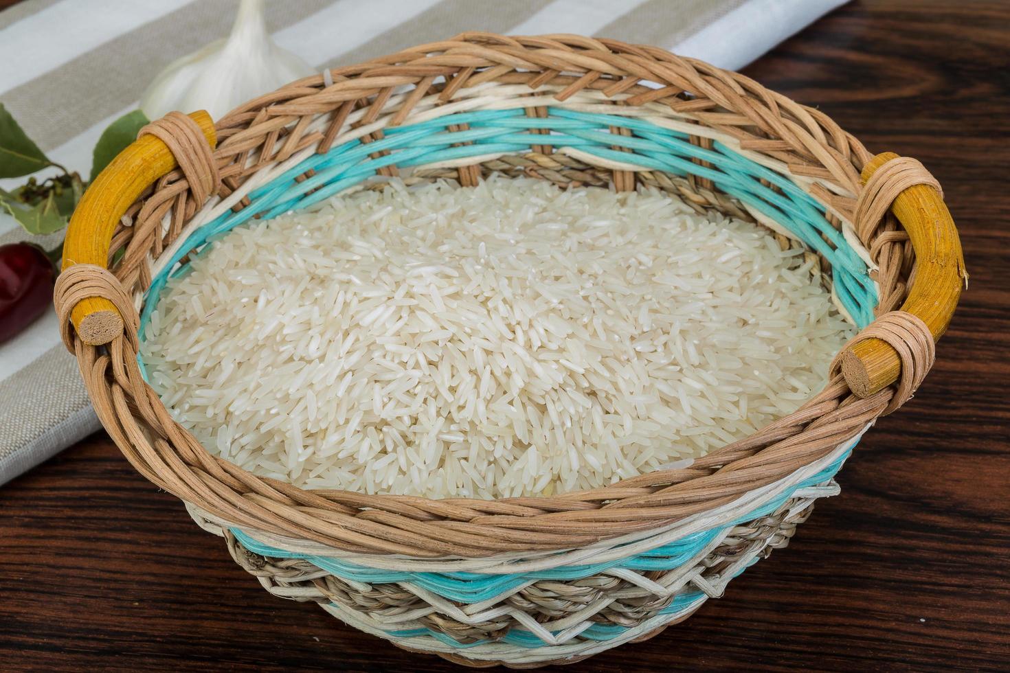 Basmati rice in a basket on wooden background photo