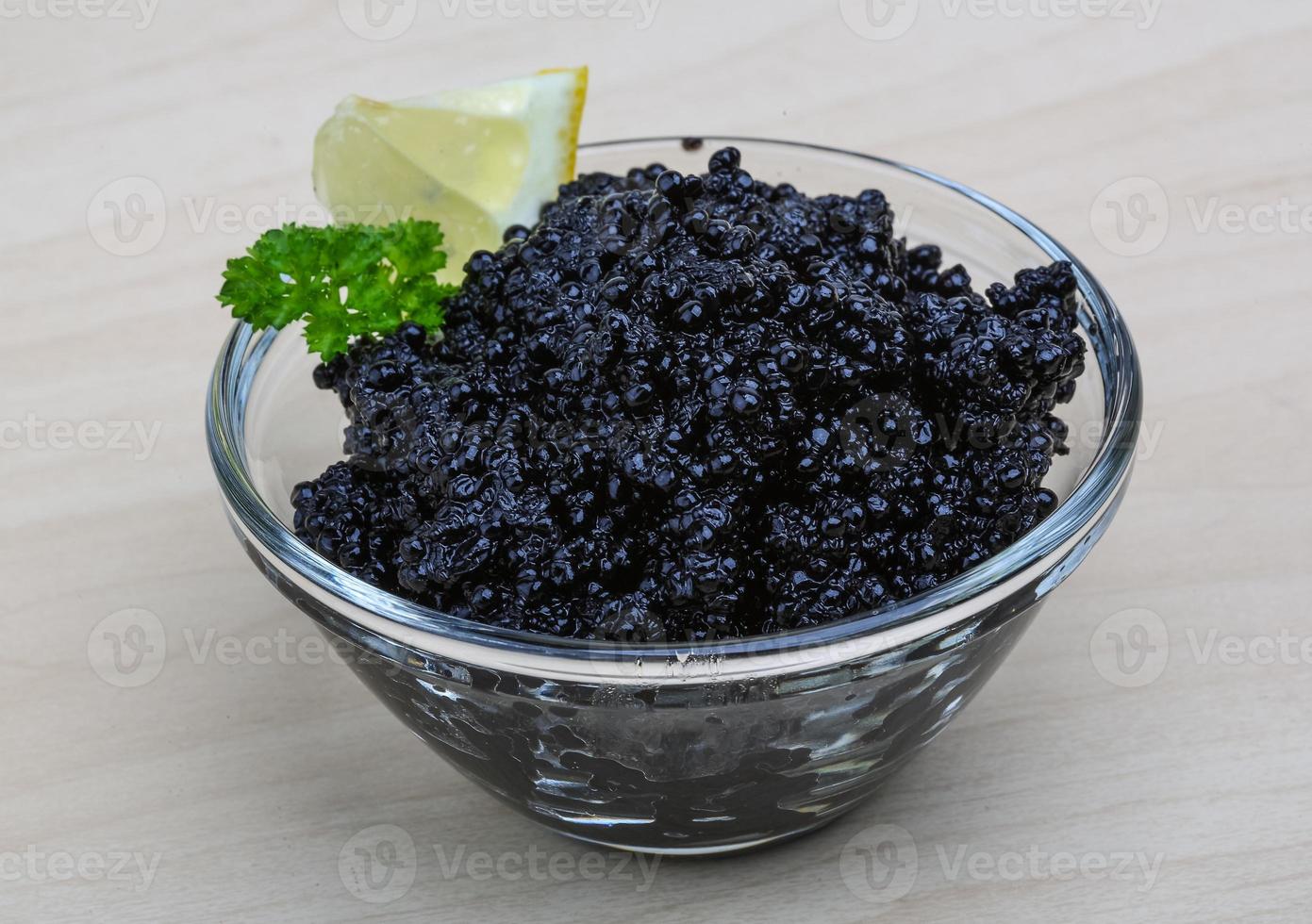 Black caviar in a bowl on wooden background photo