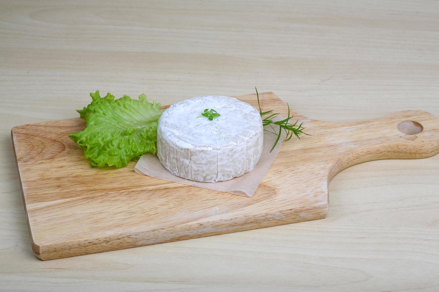 Camembert cheese on wooden board and wooden background photo