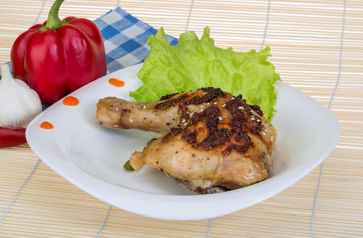 muslo de pollo asado en el plato y fondo de madera foto