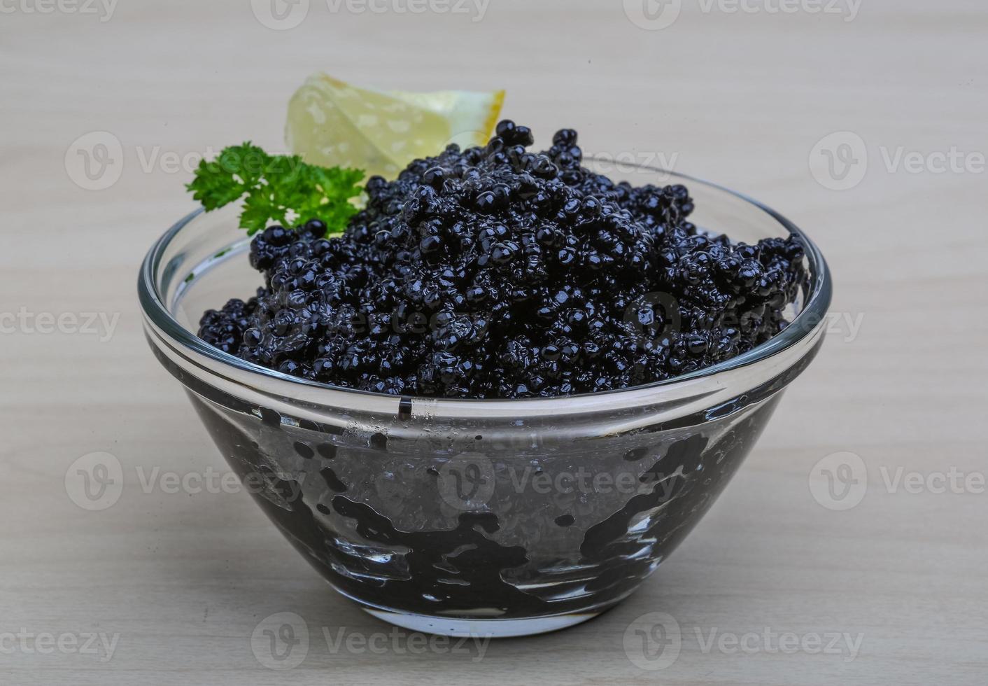 Black caviar in a bowl on wooden background photo