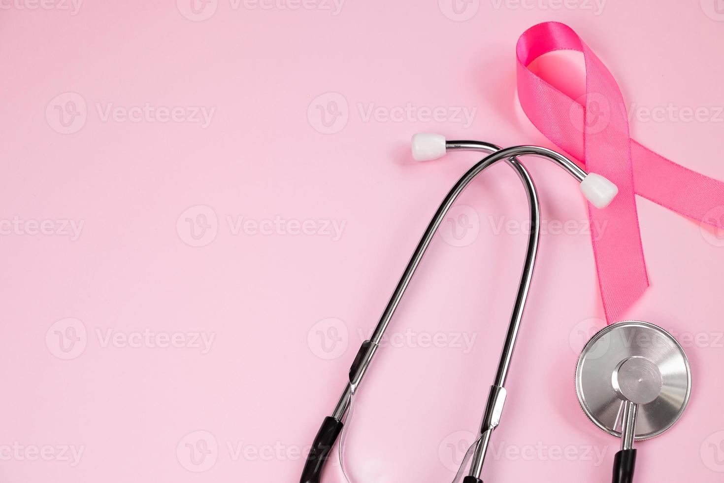 Pink ribbon and stethoscope on colored background. Breast Cancer Awareness Month. Women's health care concept. Symbol of fight against oncology. photo