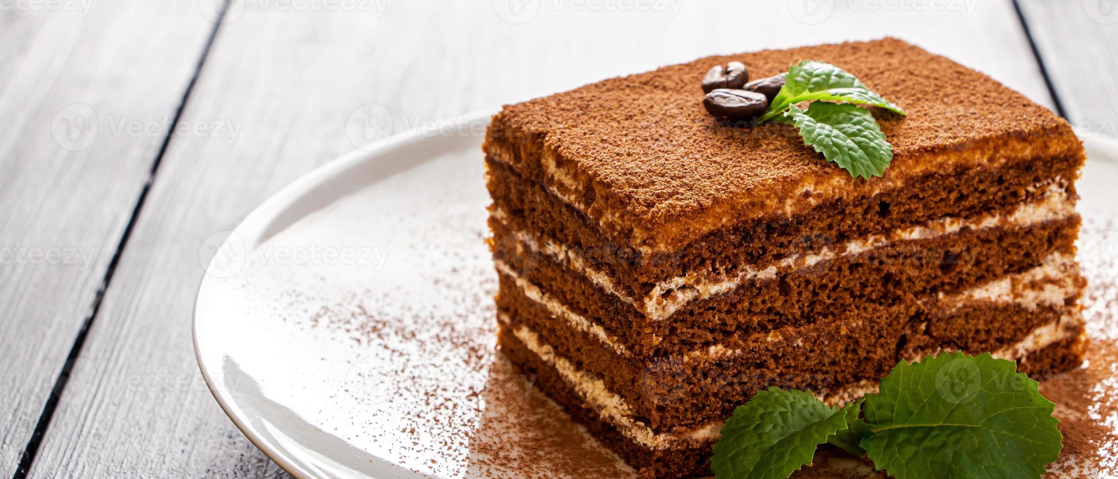 Tiramisu dessert decorated with mint on white plate. photo