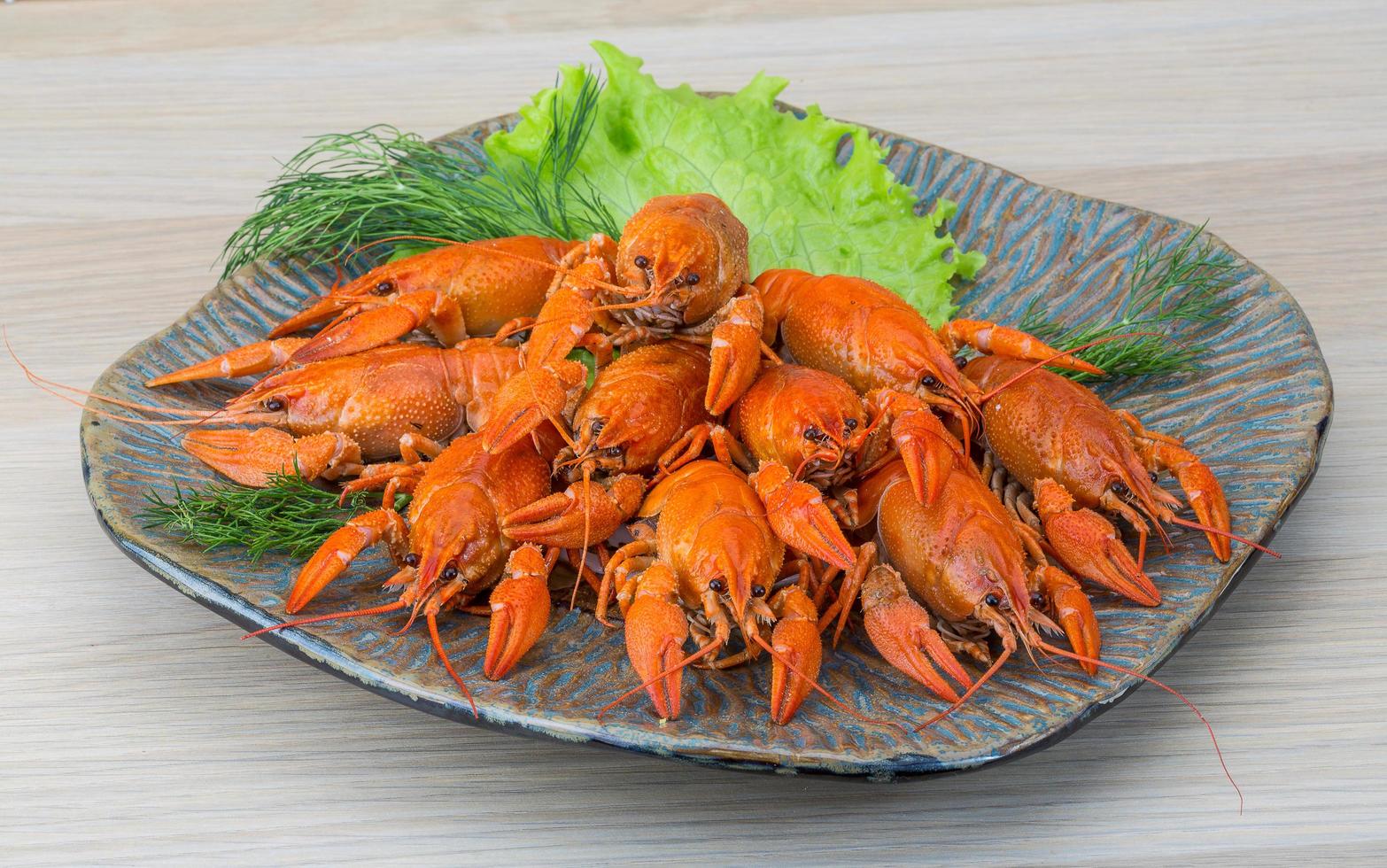 Boiled crayfish on the plate and wooden background photo