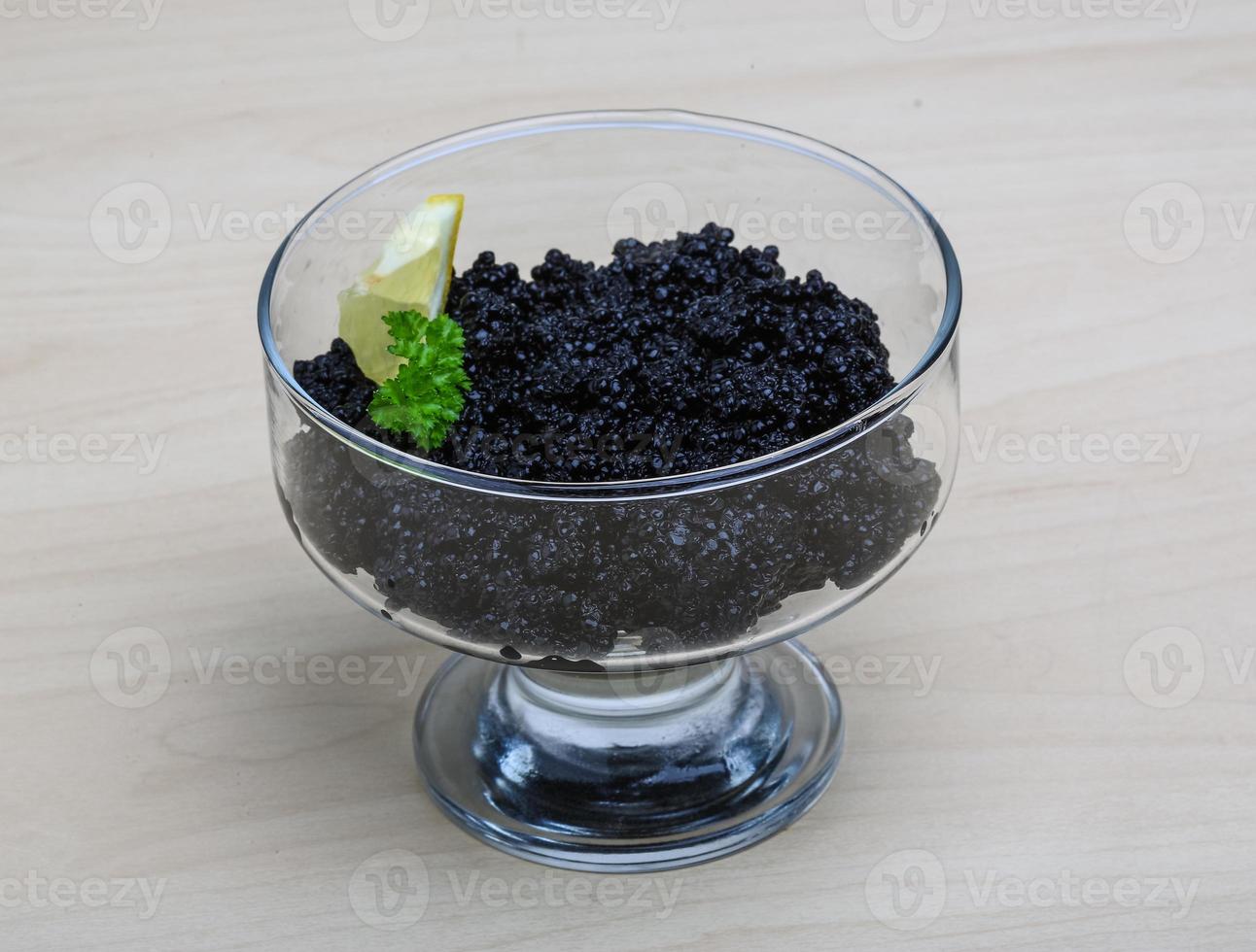 Black caviar in a bowl on wooden background photo
