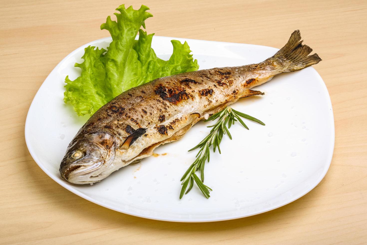 Grilled trout on the plate and wooden background photo