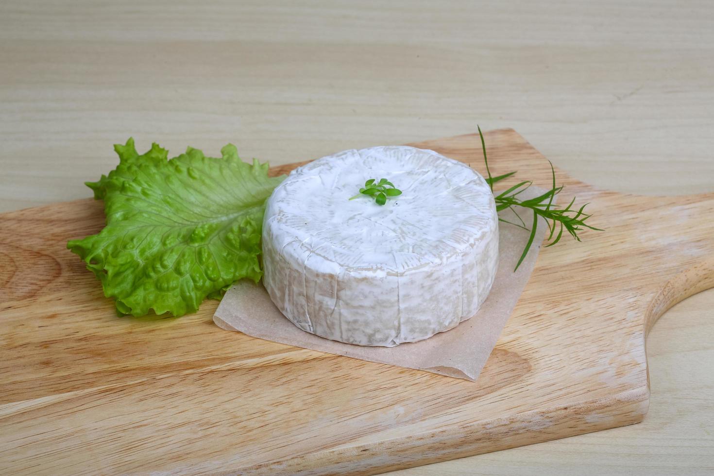 Camembert cheese on wooden board and wooden background photo