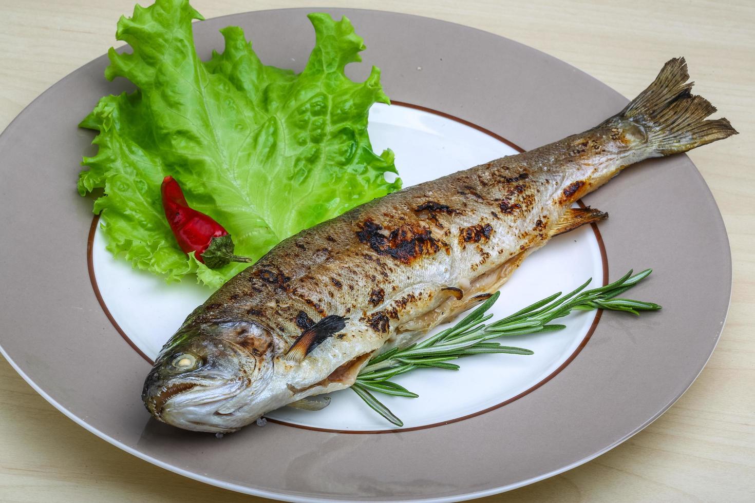 Grilled trout on the plate and wooden background photo