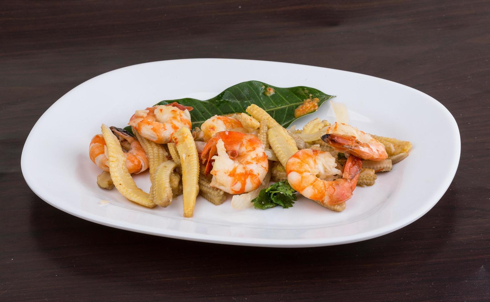 ensalada de camarones y maíz en el plato y fondo de madera foto