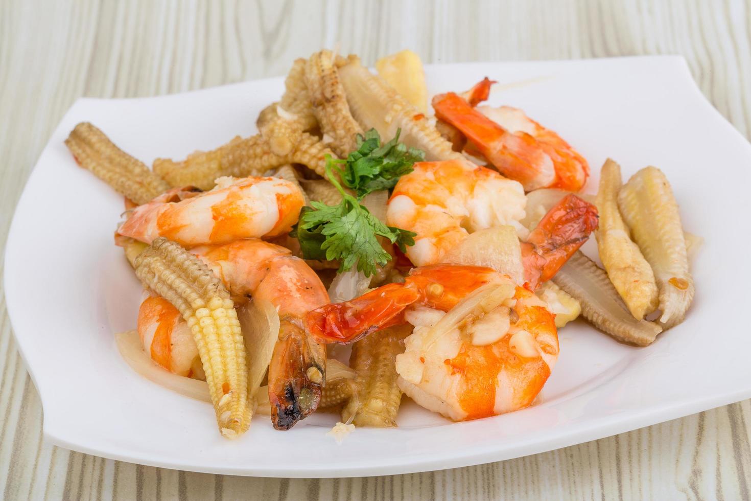 ensalada de camarones y maíz en el plato y fondo de madera foto