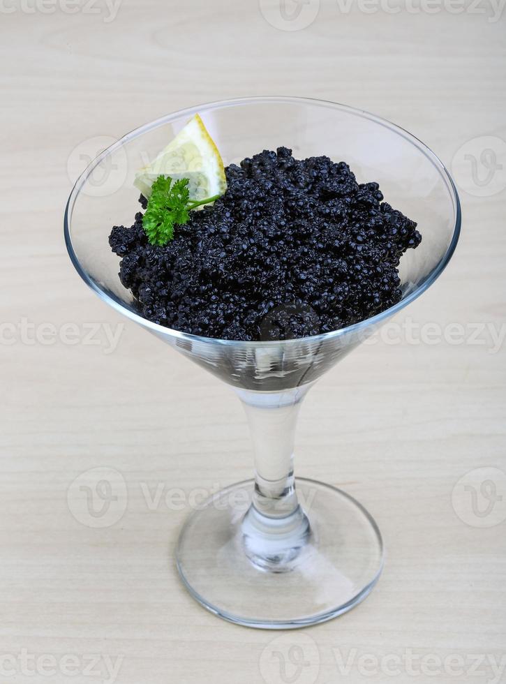 Black caviar in a bowl on wooden background photo