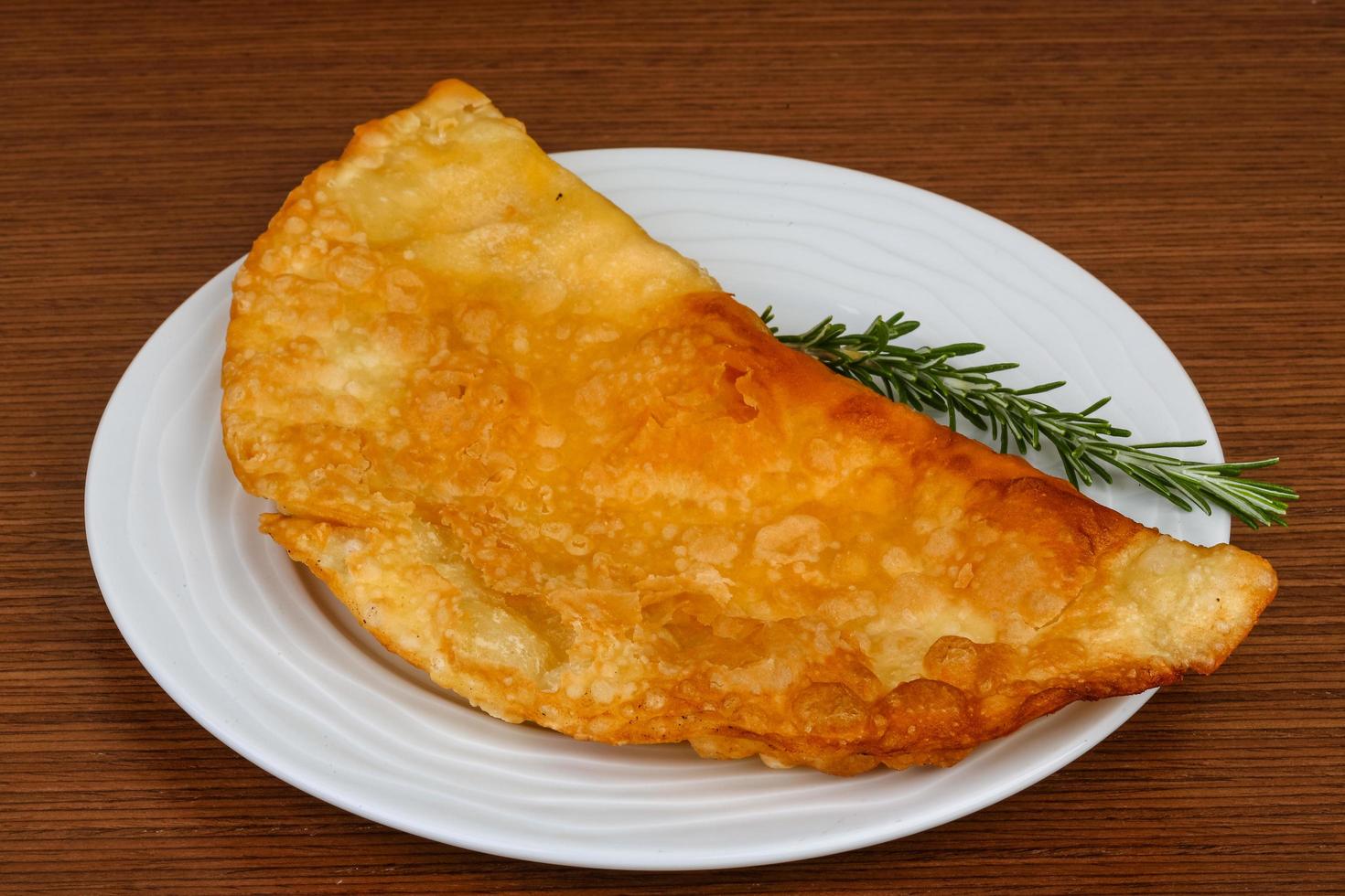 Meat Cheburek on the plate and wooden background photo