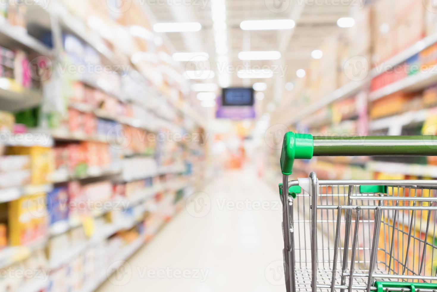 carrito de compras de supermercado verde vacío con pasillo de tienda de comestibles borroso abstracto fondo desenfocado foto