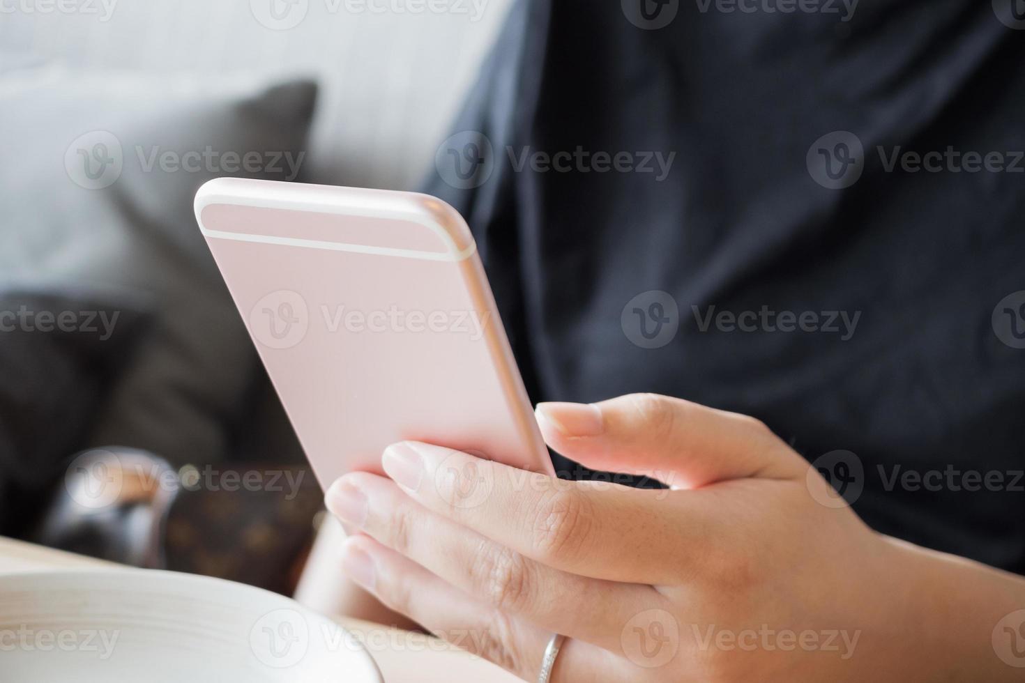 mujer con anillo de diamantes en la mano usando un teléfono inteligente en un café restaurante foto