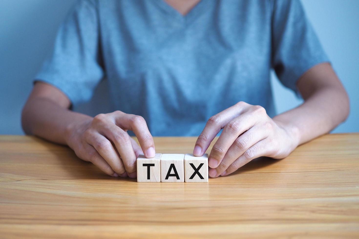 Woman holding a wooden block with the word tax , Tax finance concept. photo