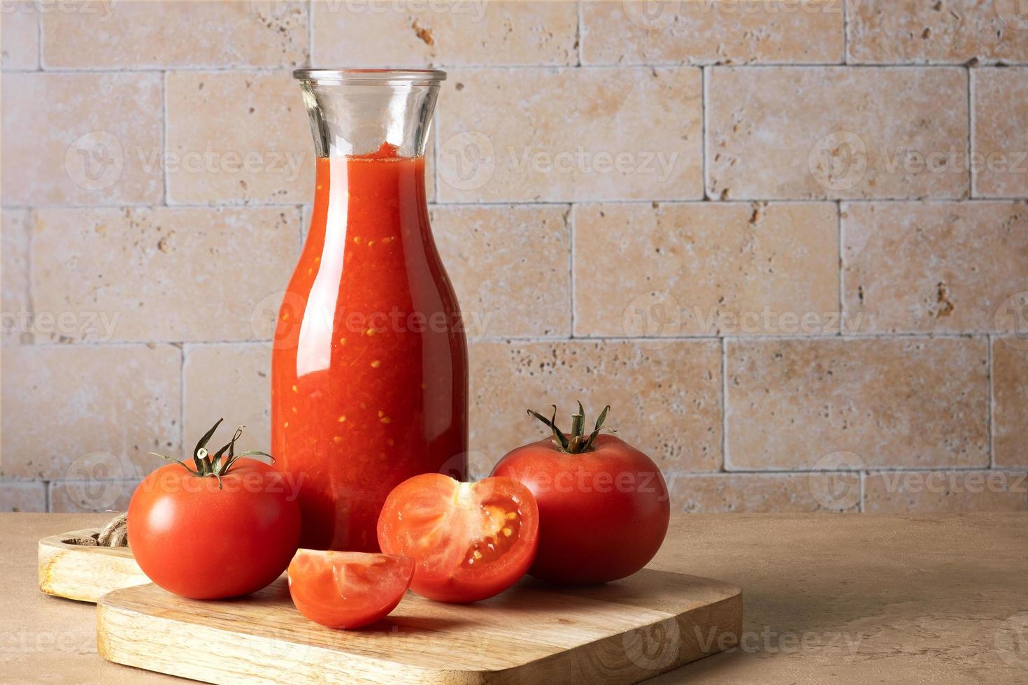 botella de vidrio con salsa de tomate casera y tomates maduros foto