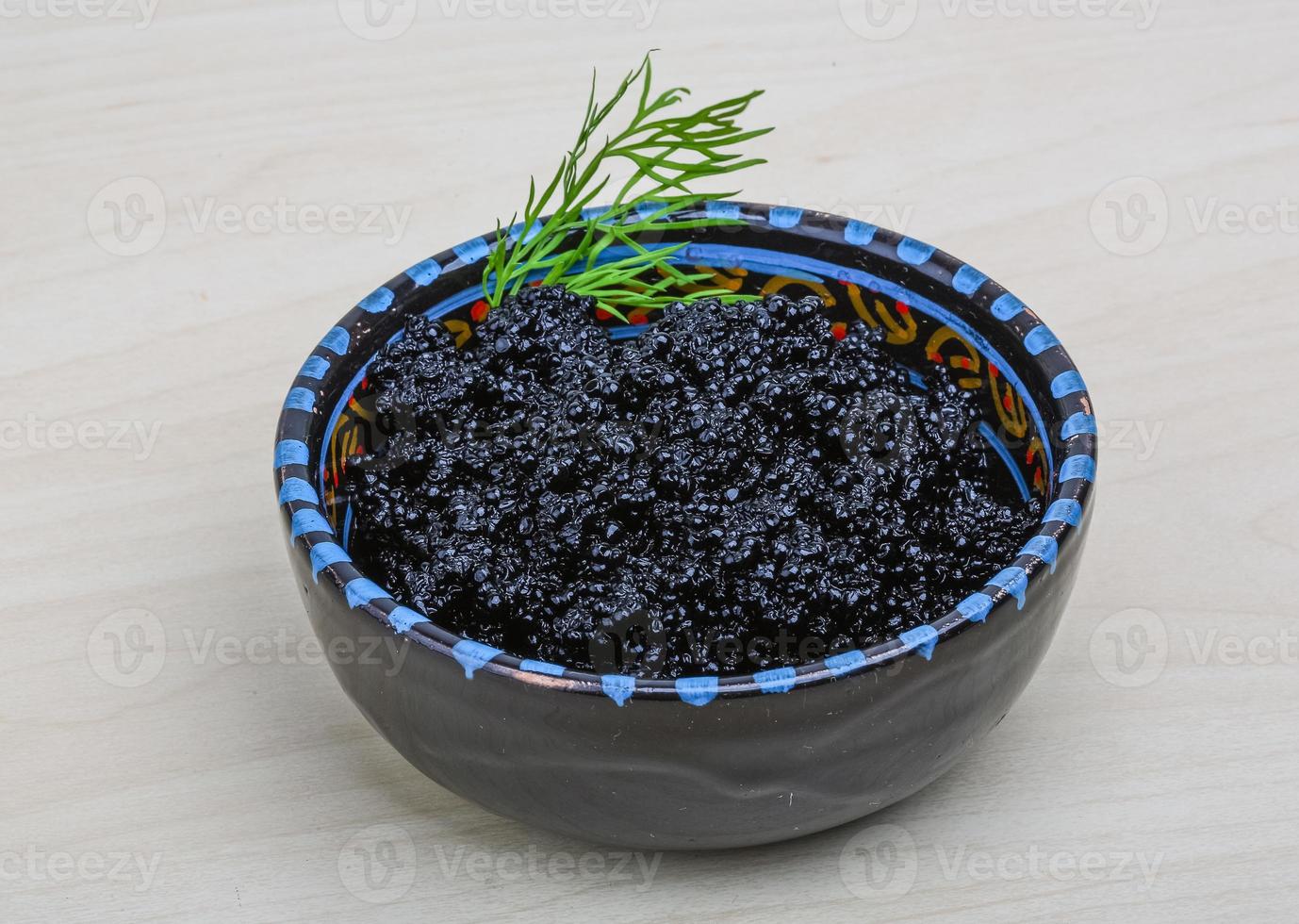 Black caviar in a bowl on wooden background photo