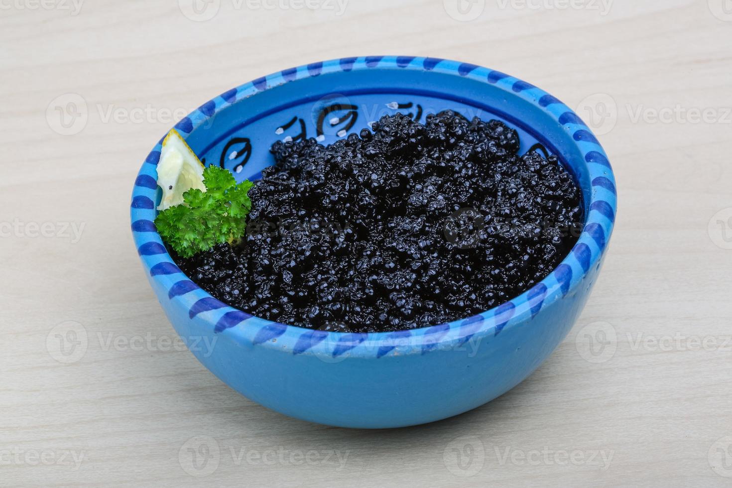 Black caviar in a bowl on wooden background photo