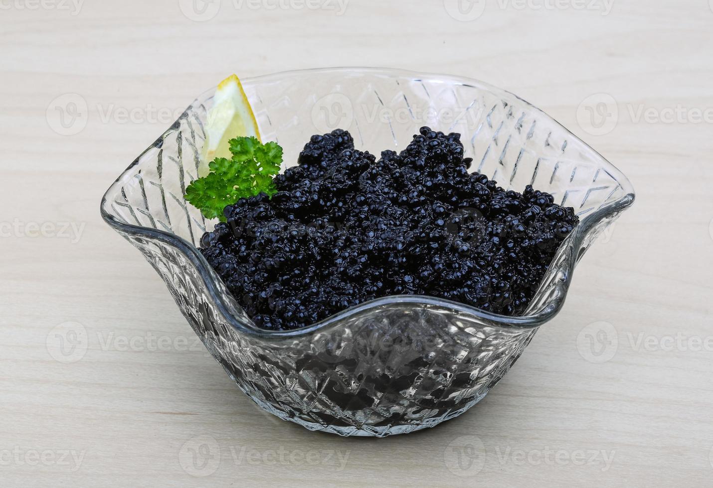 Black caviar in a bowl on wooden background photo