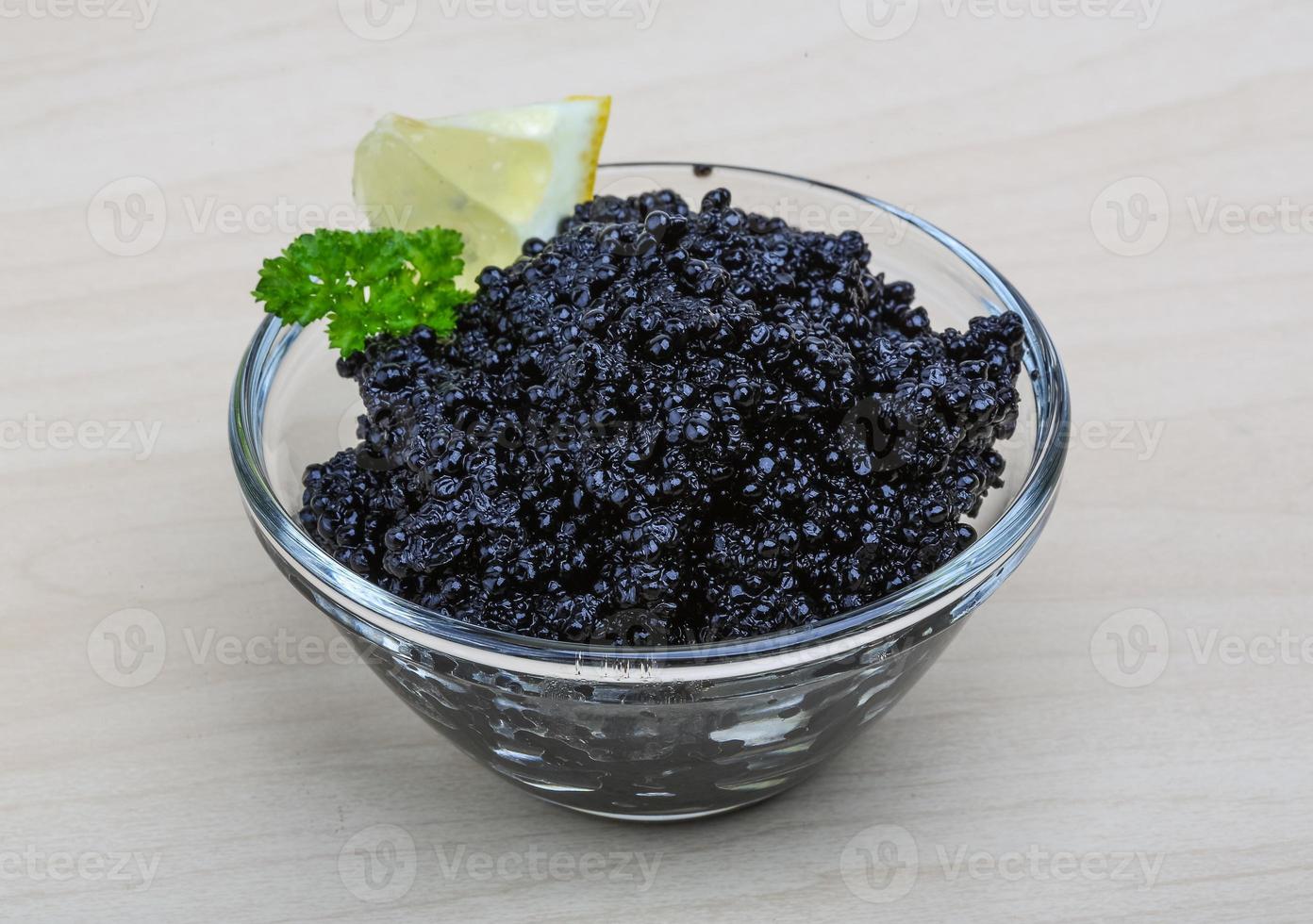 Black caviar in a bowl on wooden background photo