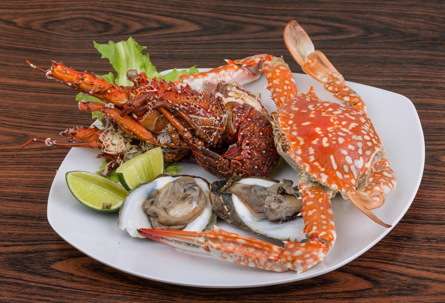 Spiny lobster, crab and oyster on the plate and wooden background photo