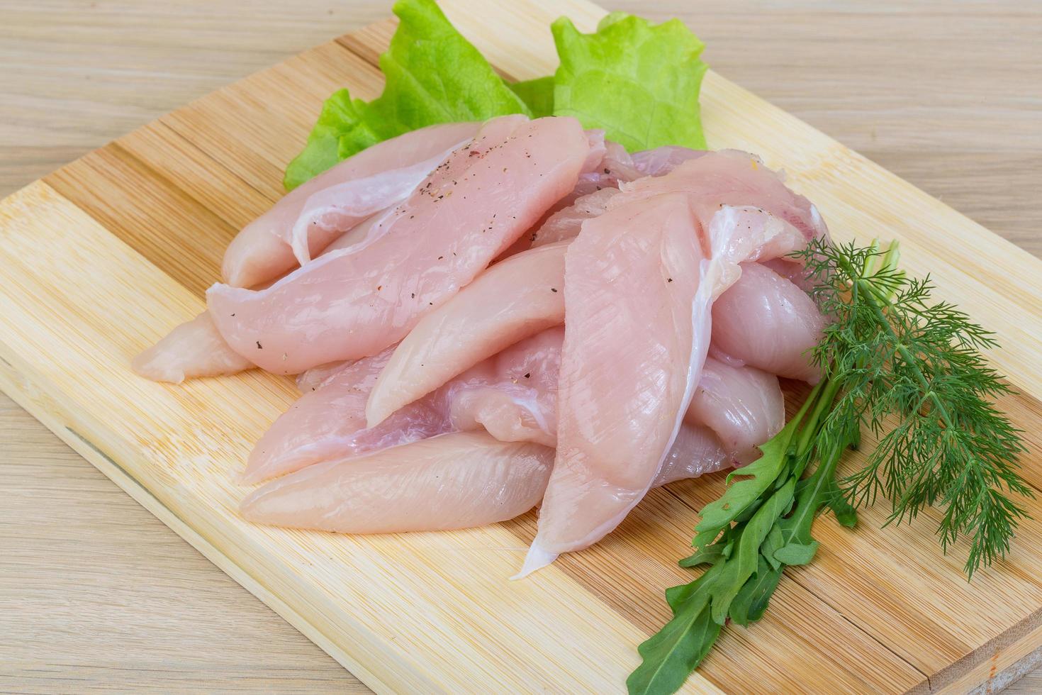 Raw chicken breast on wooden board and wooden background photo