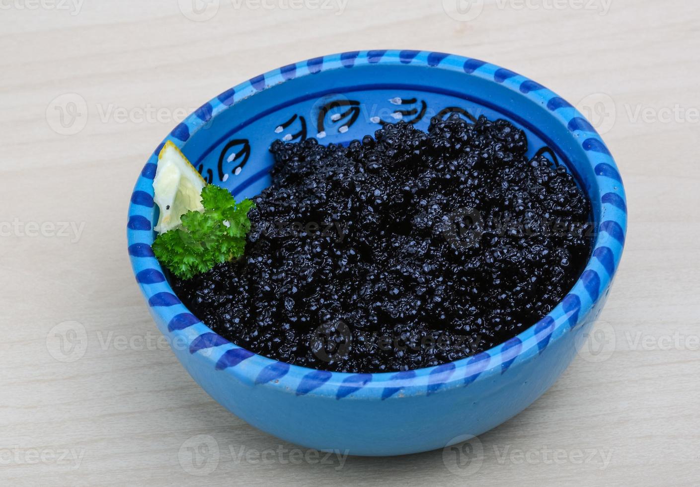 Black caviar in a bowl on wooden background photo