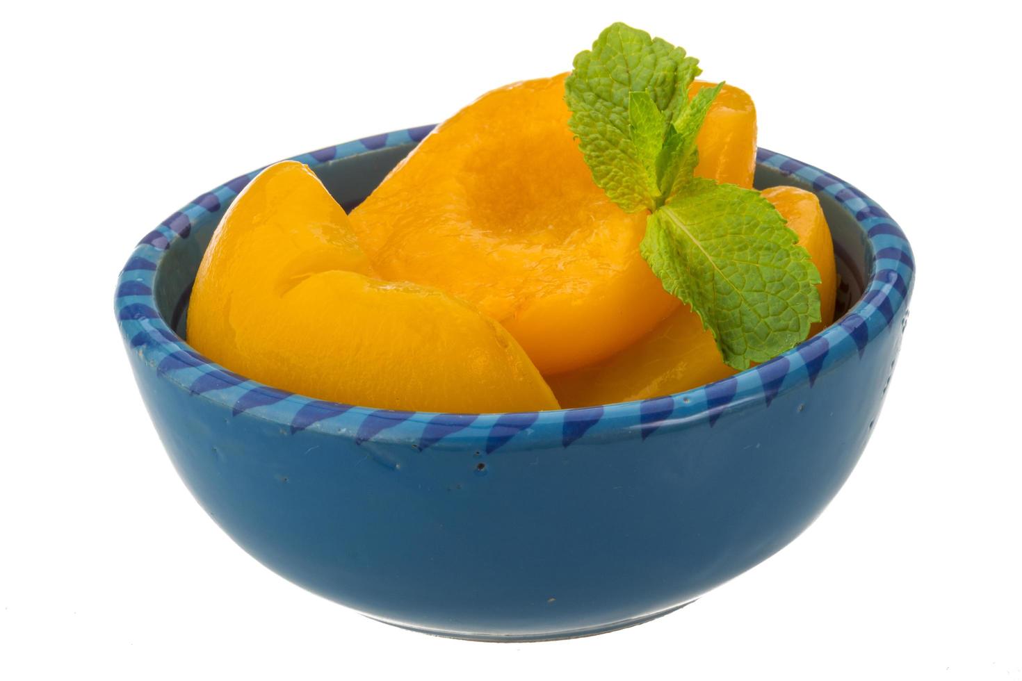 Marinated peaches in a bowl on white background photo