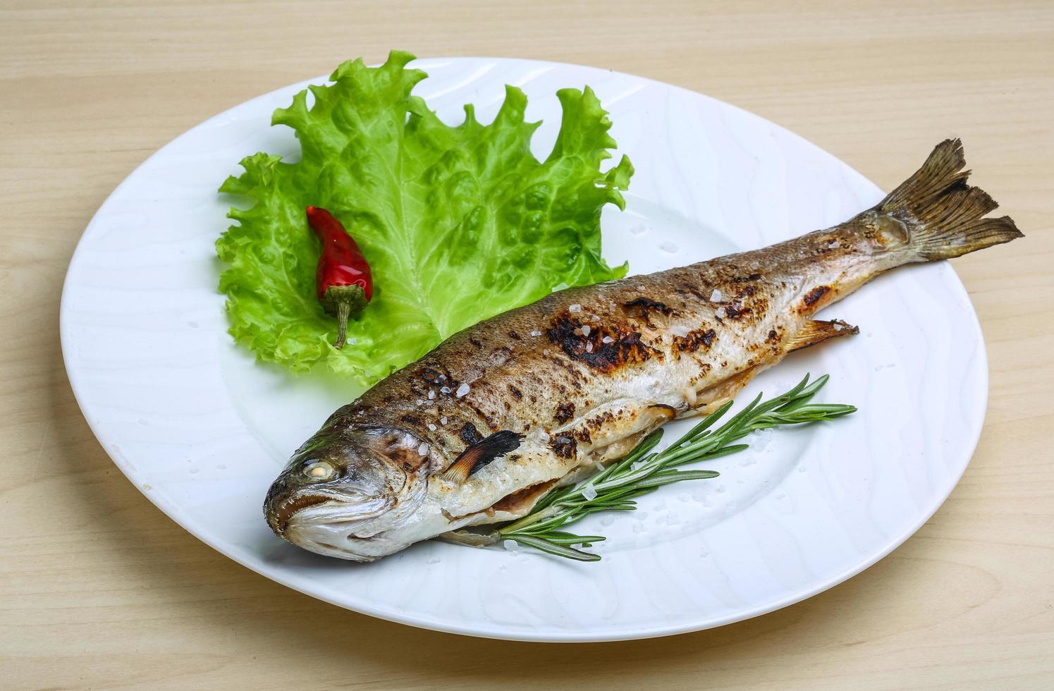 Grilled trout on the plate and wooden background photo