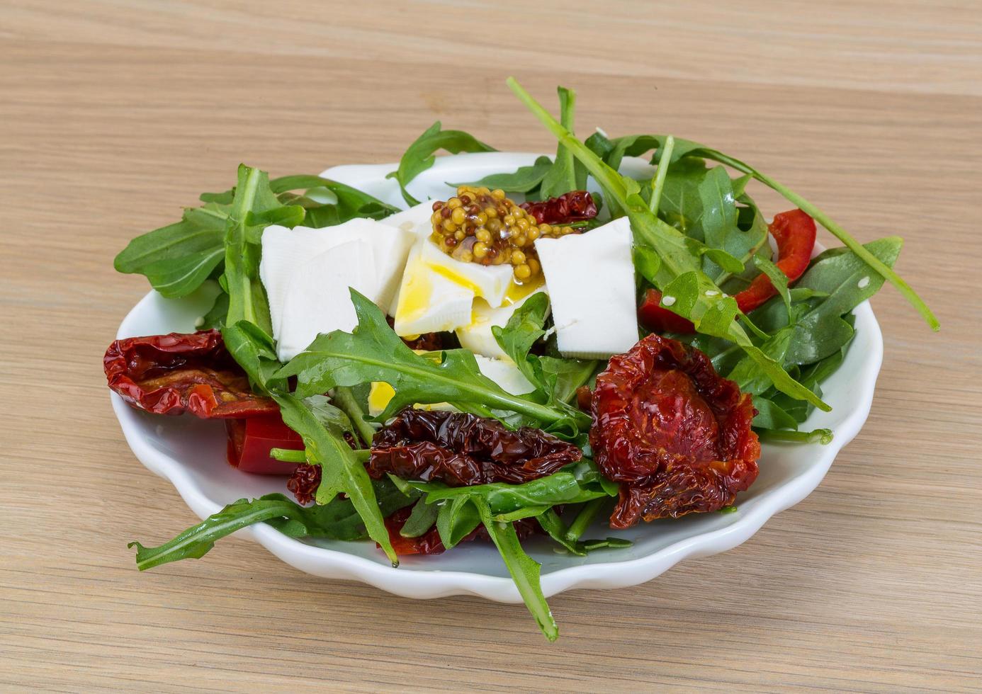 Salad with dried tomato on the plate and wooden background photo