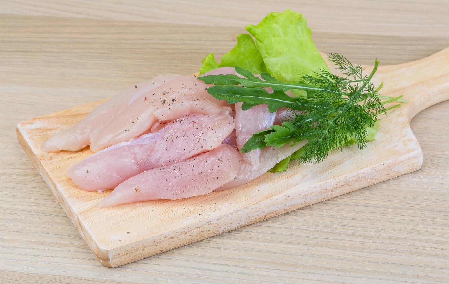 Raw chicken breast on wooden board and wooden background photo