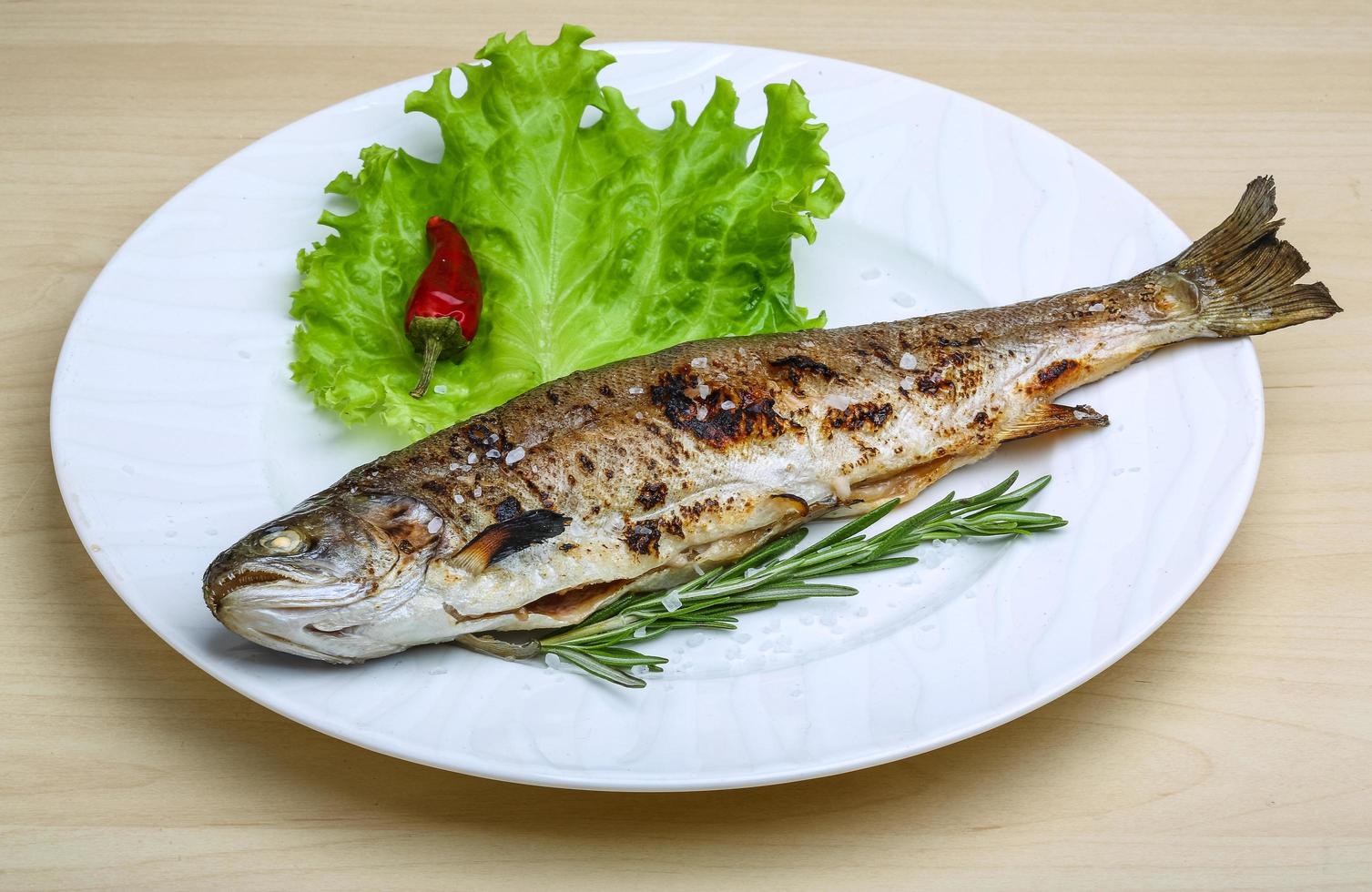 Grilled trout on the plate and wooden background photo