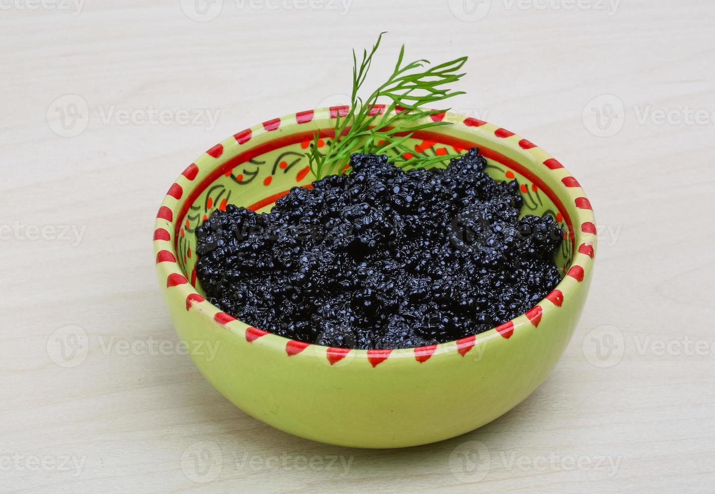 Black caviar in a bowl on wooden background photo