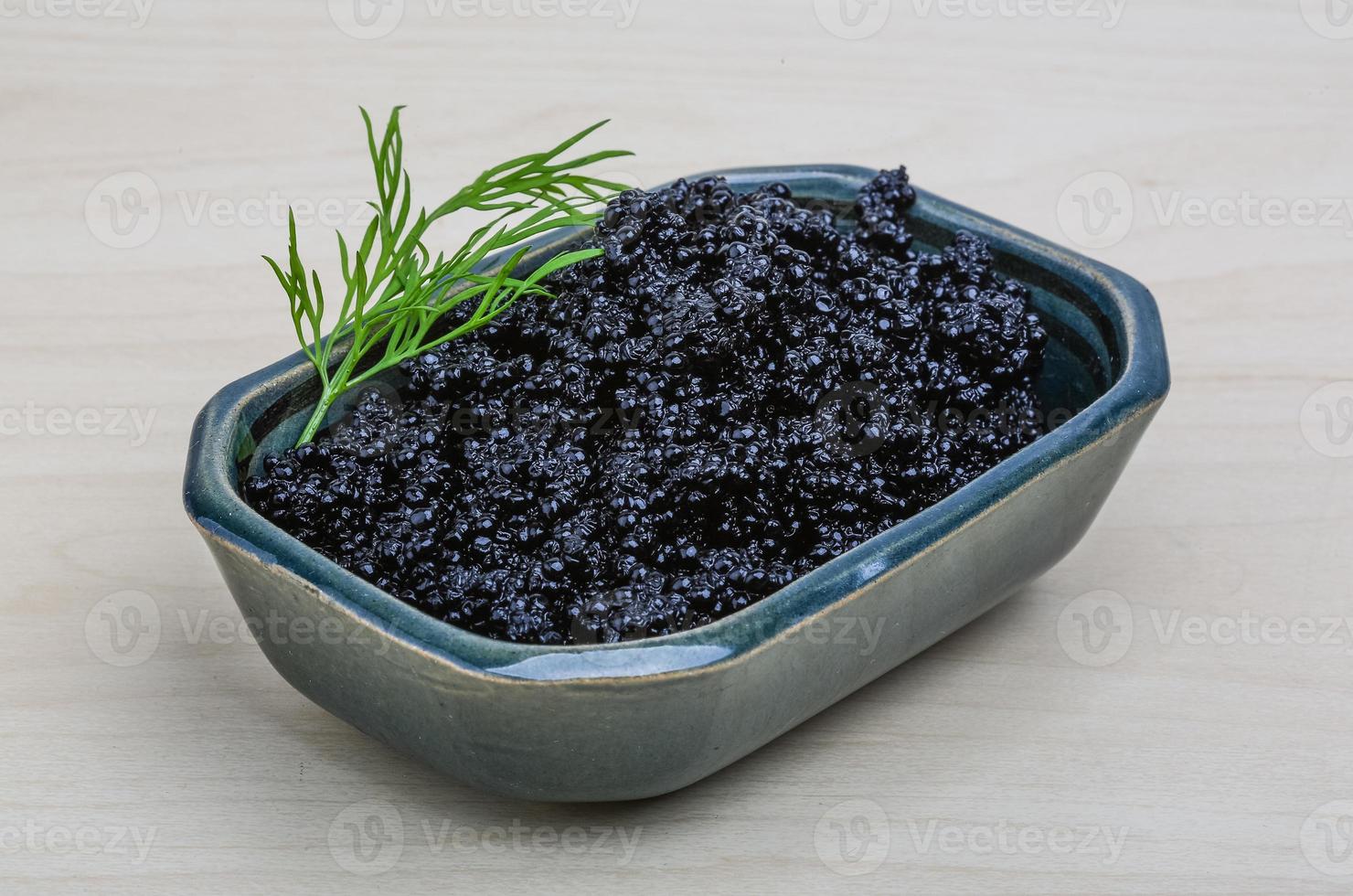 Black caviar in a bowl on wooden background photo