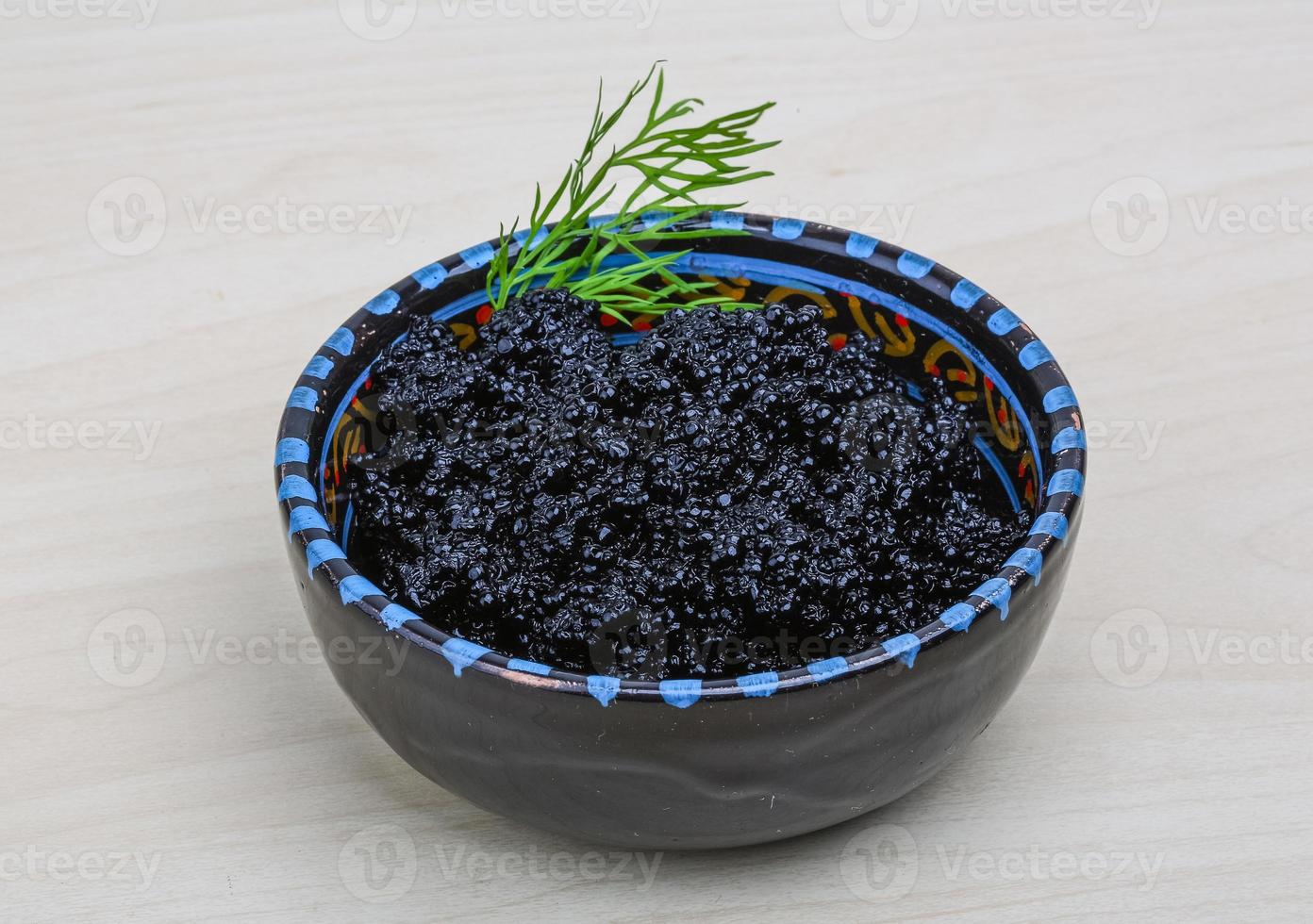 Black caviar in a bowl on wooden background photo