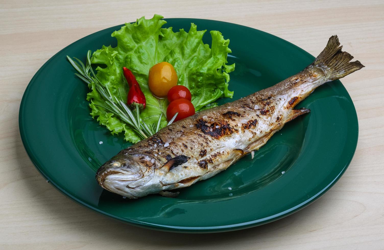 Grilled trout on the plate and wooden background photo