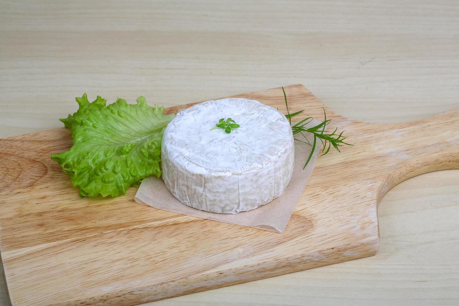 Camembert cheese on wooden board and wooden background photo