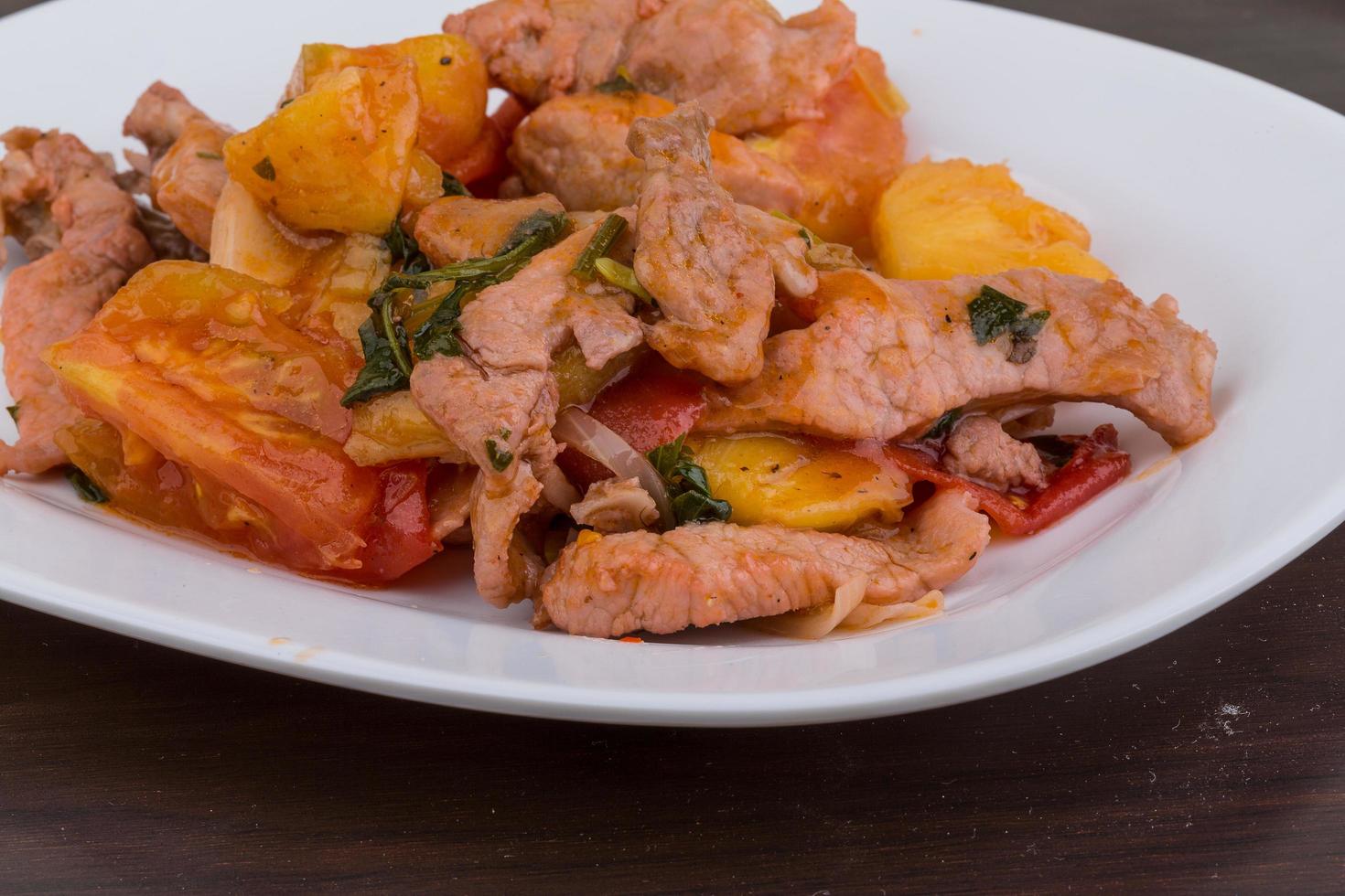 Pork and pineapple salad on the plate and wooden background photo
