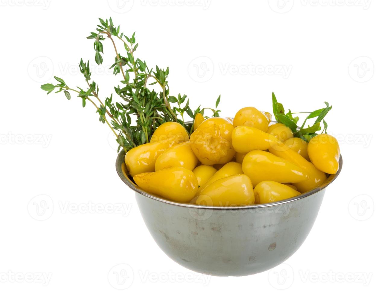 Yellow marinated pepper in a bowl on white background photo