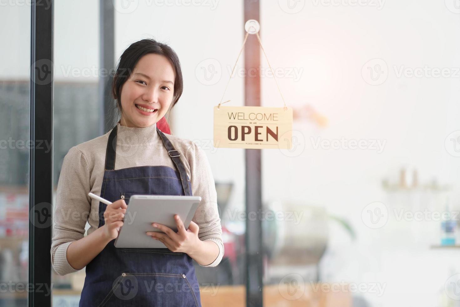 Startup successful small business owner sme beauty girl stand with tablet smartphone in coffee shop restaurant. Portrait of asian tan woman barista cafe owner. SME entrepreneur seller business concept photo