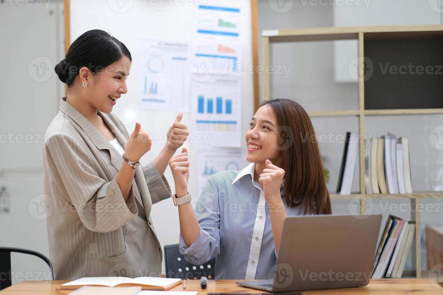 Happy business asian people are keeping arms raised hi five and expressing joyful while standing. achieving goals. photo
