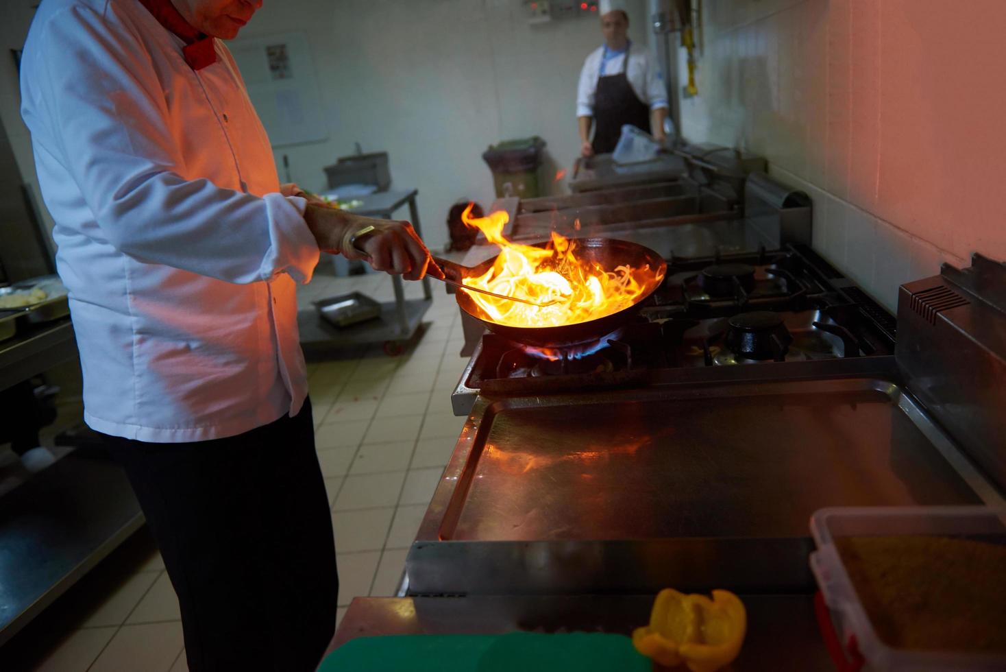 chef en la cocina del hotel prepara comida con fuego foto