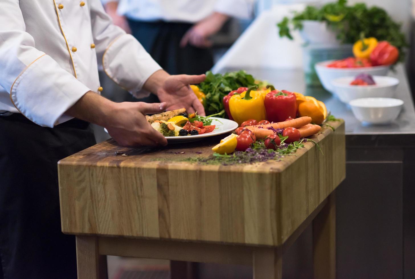 manos del chef sosteniendo un plato de filete de salmón frito foto