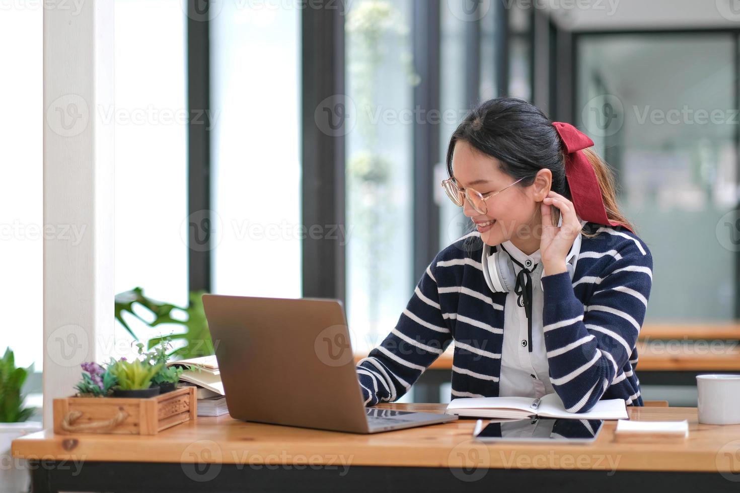 estudiante aprendiendo en una computadora portátil en el interior: curso educativo o capacitación, seminario, concepto de educación en línea, mujer asiática con una computadora portátil moderna y auriculares aprendiendo en casa foto