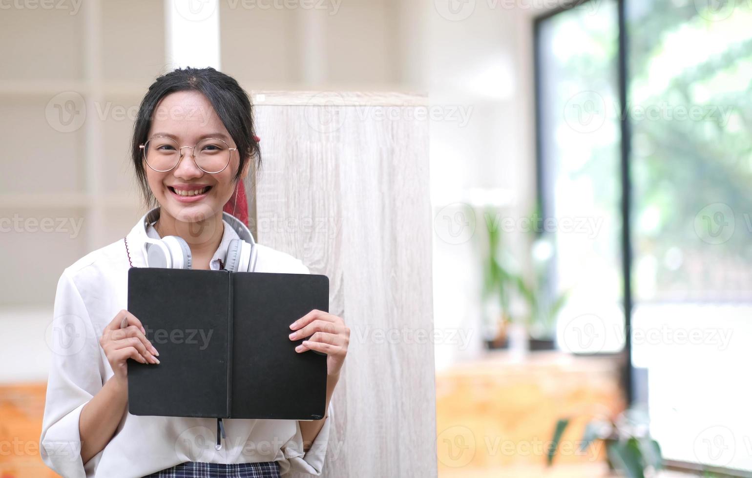 Young asian business woman is standing at a desk and taking notes in a notebook. The concept of education and technology. photo