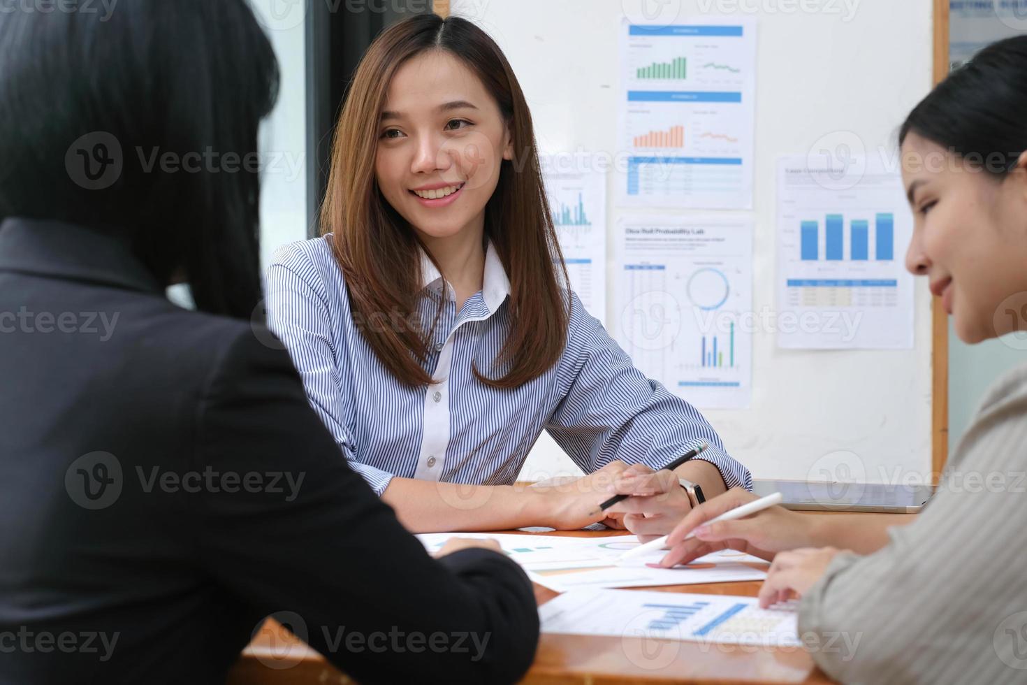 A young asian woman is having a business meeting with her team colleagues in a conference room. photo