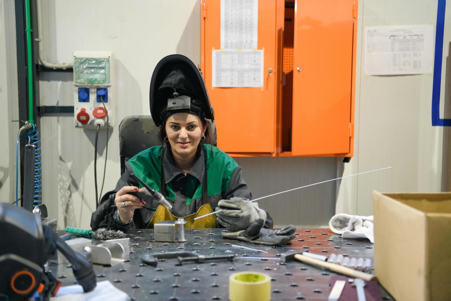 A woman employed in a modern factory for the production and processing of metals in a work uniform welds metal materials photo