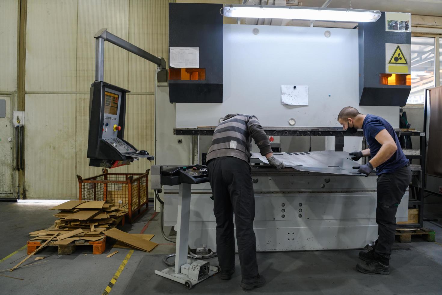 two workers wearing a protective mask due to a coronavirus pandemic, working in a modern factory and preparing a program and materials for a cnc machine photo